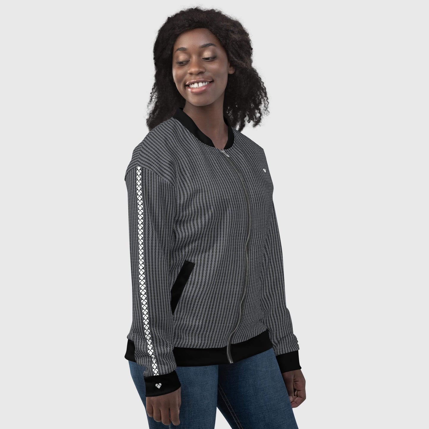 side view of a model wearing A limited edition black bomber jacket by CRiZ AMOR with a bunch of little heart-shaped geometrical logos in two shades of gray
